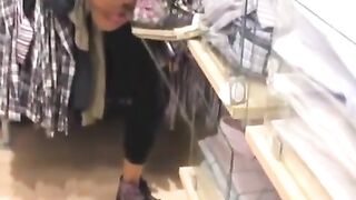 Girl pissing hidden in a clothing store.